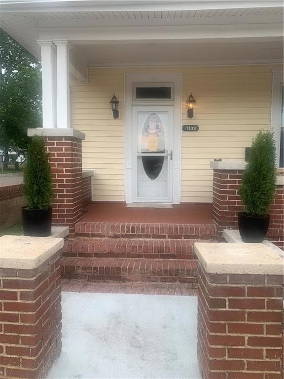 Doorway to property featuring covered porch