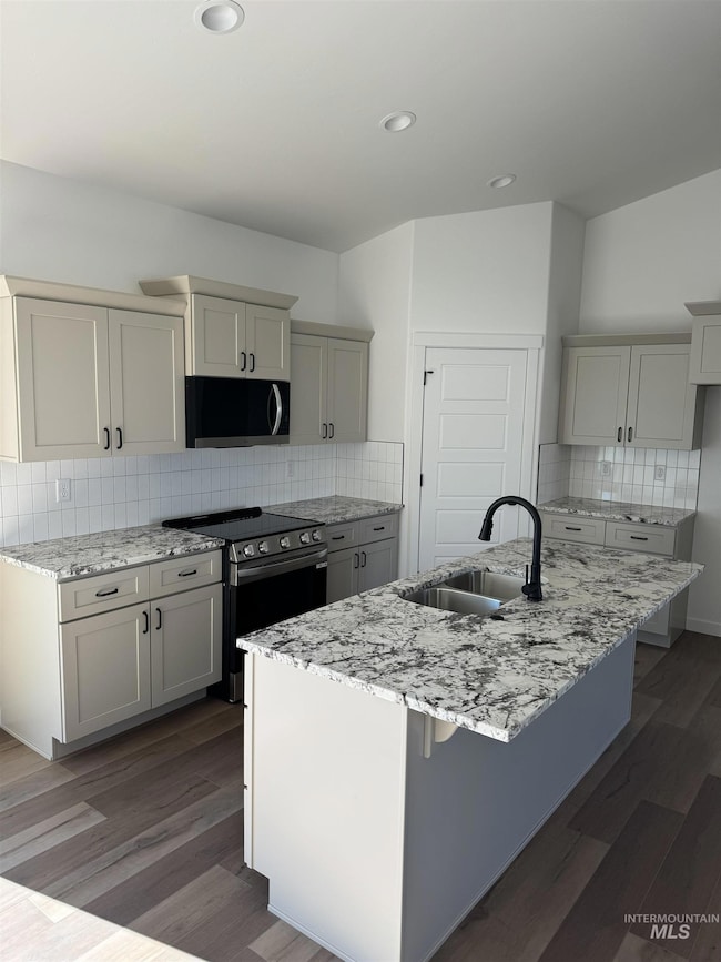 Kitchen with light stone counters, decorative backsplash, stainless steel range with electric stovetop, gray cabinetry, and recessed lighting