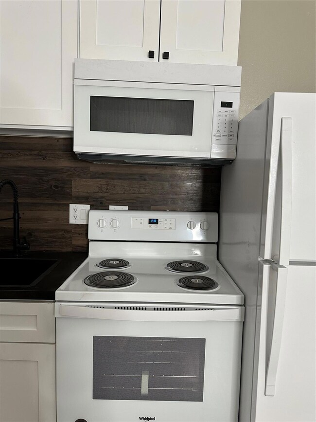 Kitchen featuring white cabinetry, white electric 