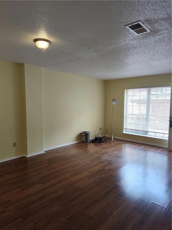 Empty room featuring dark wood-style flooring and a textured ceiling