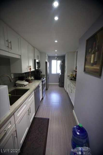 Kitchen with stainless steel appliances, light countertops, white cabinetry, and a sink