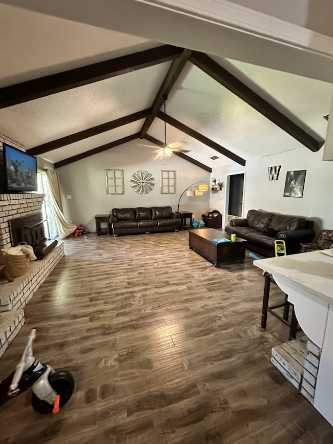 Living room with a fireplace, dark wood finished floors, and ceiling fan