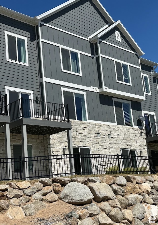 View of property exterior with stone siding, board and batten siding, and a patio