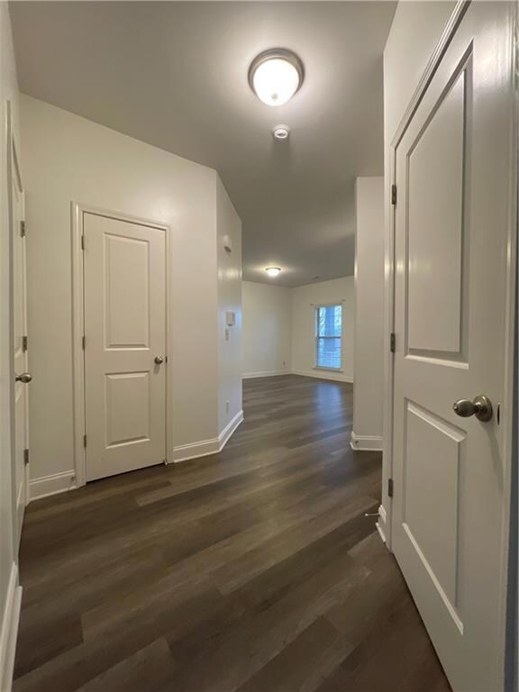 Hallway with baseboards and dark wood-style floors