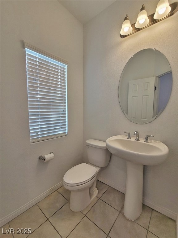 Half bathroom with toilet, tile patterned flooring