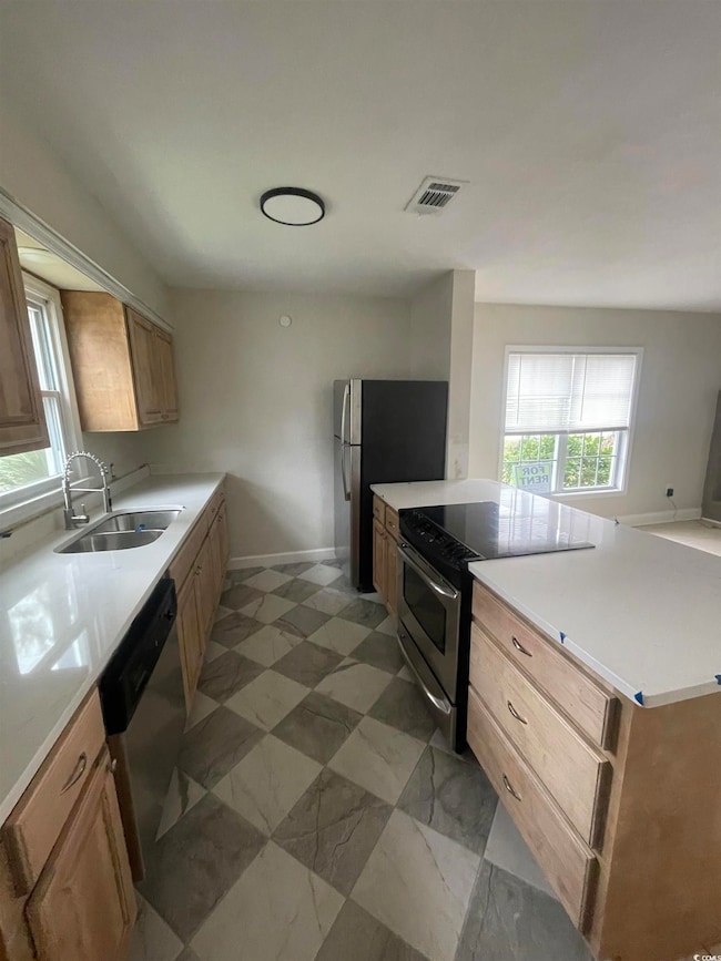 Kitchen featuring stainless steel appliances, light stone countertops, a peninsula, and light brown cabinets