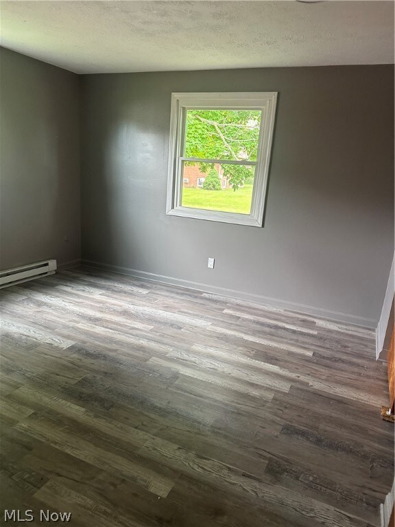 Bedroom featuring a textured ceiling, hardwood / wood-style floors, and a baseboard radiator
