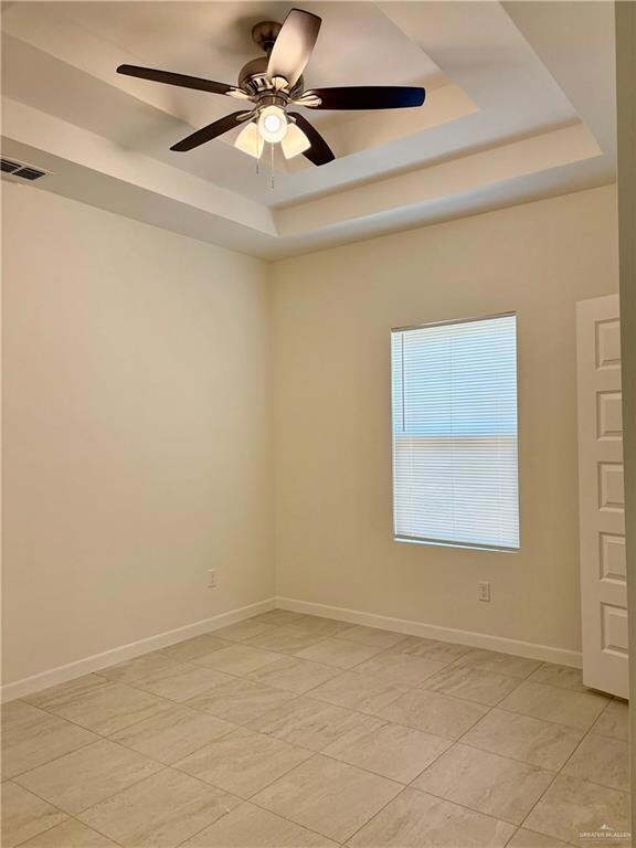 Spare room with a tray ceiling and a ceiling fan
