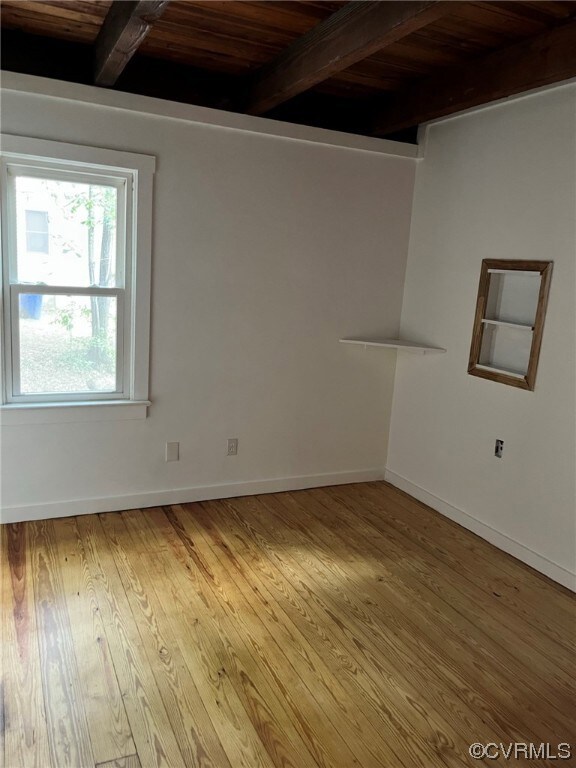 Wood floored empty room with wood beam ceiling and