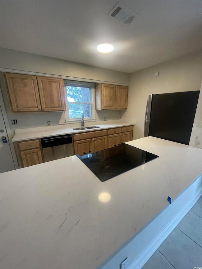 Kitchen with appliances with stainless steel finishes, tile patterned floors, and light stone countertops
