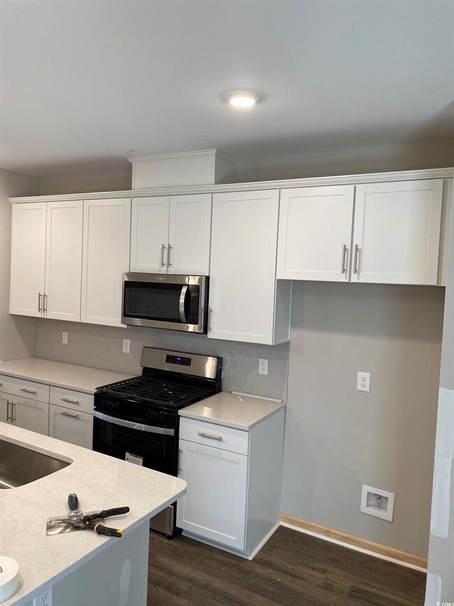 Kitchen with dark wood-type flooring, tasteful bac