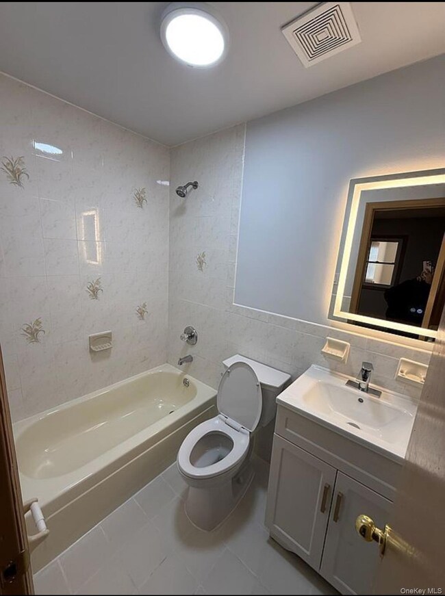 Bathroom featuring tile walls, vanity, bathtub / shower combination, and tile patterned floors