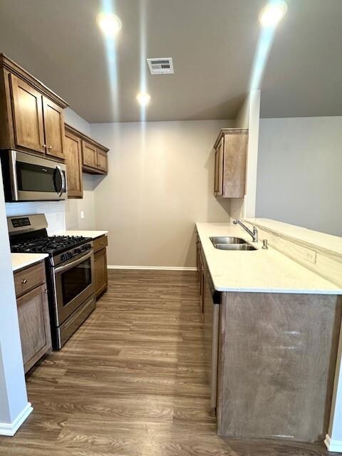 Kitchen with a sink, a peninsula, visible vents, b