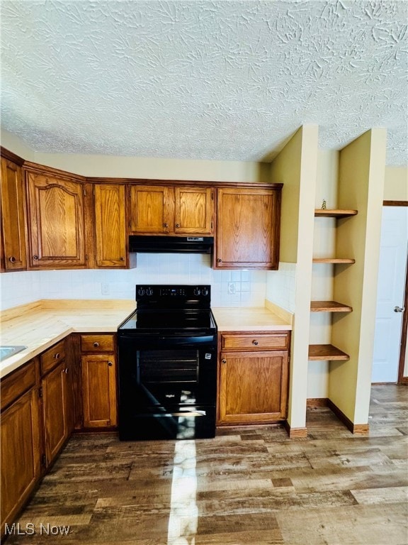 Kitchen featuring black electric range, tasteful backsplash, light countertops, brown cabinets, and dark wood-style floors