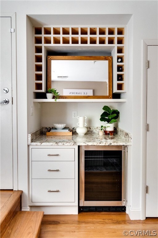 Bar featuring light stone counters, light hardwood