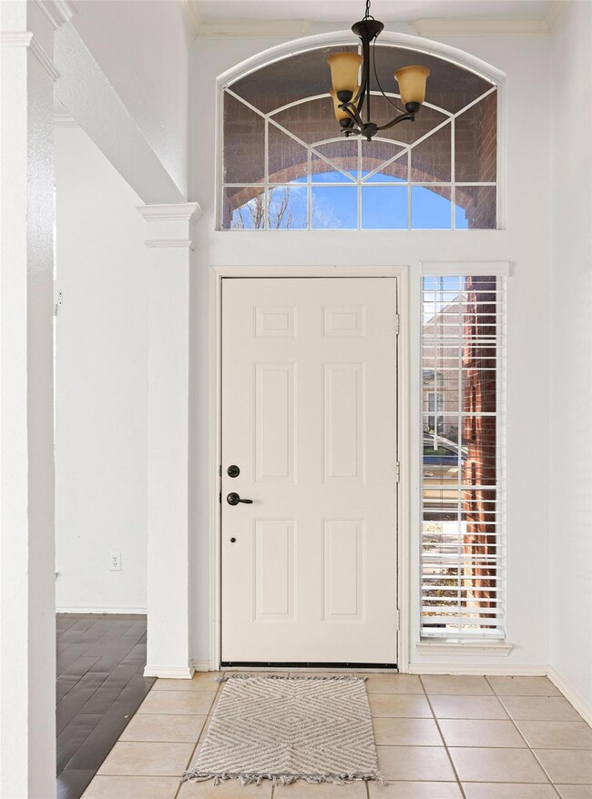 Tiled foyer entrance featuring baseboards, an invi