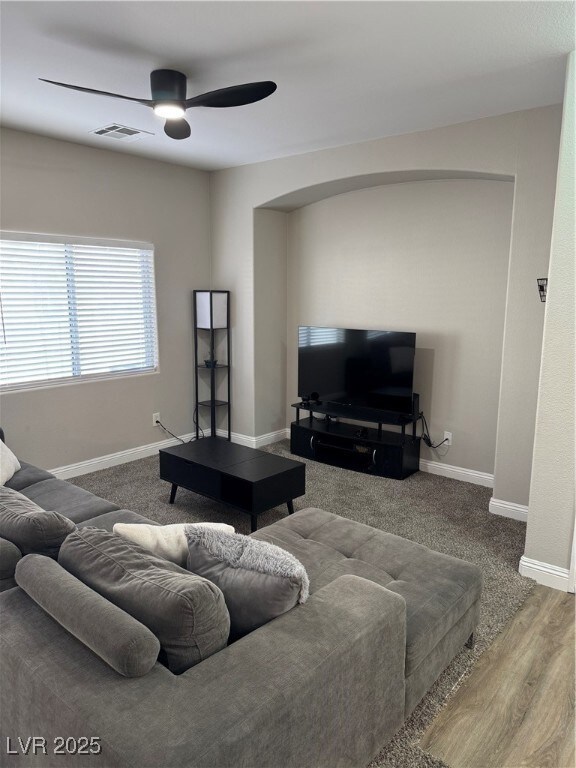 Living area featuring a ceiling fan, baseboards, w