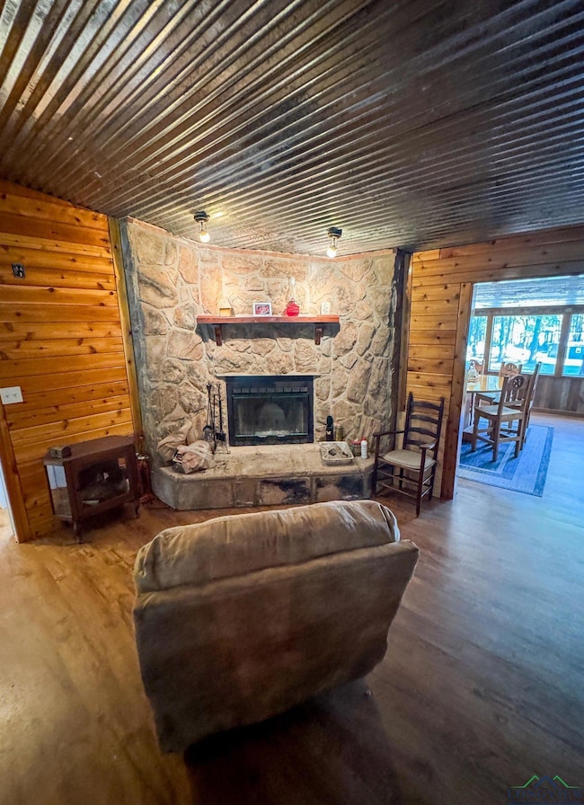 Living room with wood walls, wood finished floors, a fireplace, and wooden ceiling