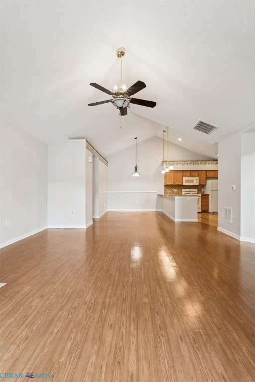 Unfurnished living room with vaulted ceiling, light wood finished floors, and ceiling fan