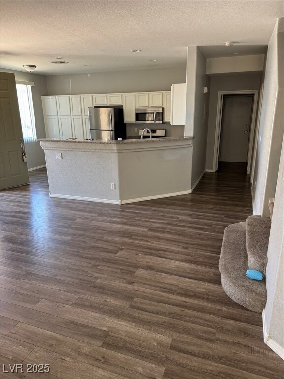 Kitchen with white cabinets, refrigerator, dark wo