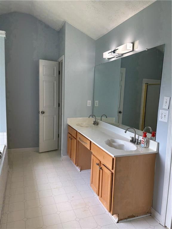 Bathroom featuring lofted ceiling and double vanit
