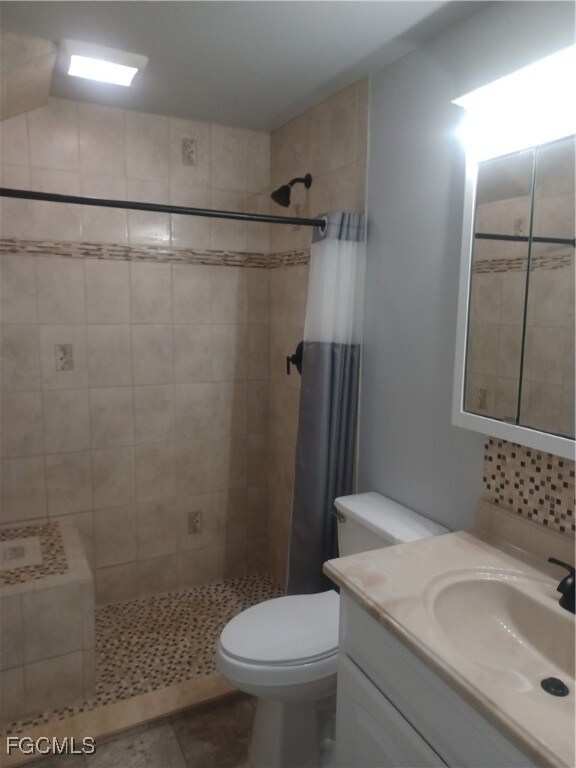 Full bathroom featuring vanity, tiled shower, and tile patterned floors