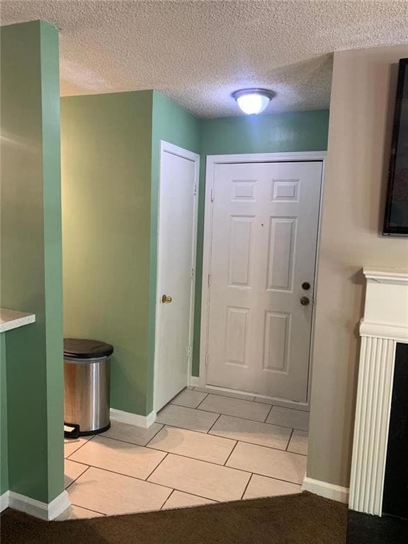 Foyer with light tile patterned floors and a textured ceiling