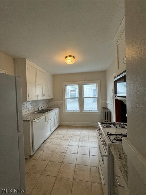 Kitchen featuring light tile floors, fridge, light stone countertops, range, and white cabinets