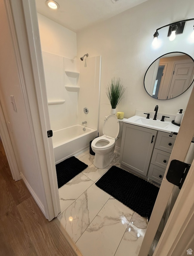 Bathroom with marble look tiles, vanity, and bathtub / shower combination