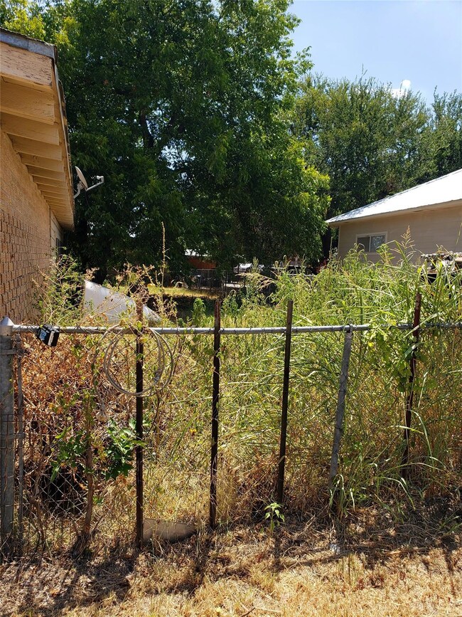 Fence near the carport, with view of the expansive backyard.