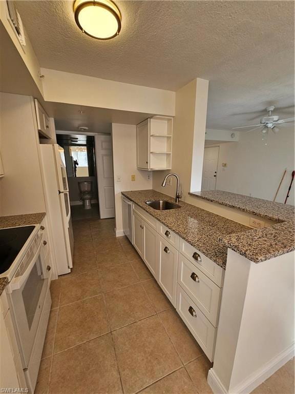 Kitchen featuring white cabinetry, dark stone countertops, a textured ceiling, stove, and a peninsula