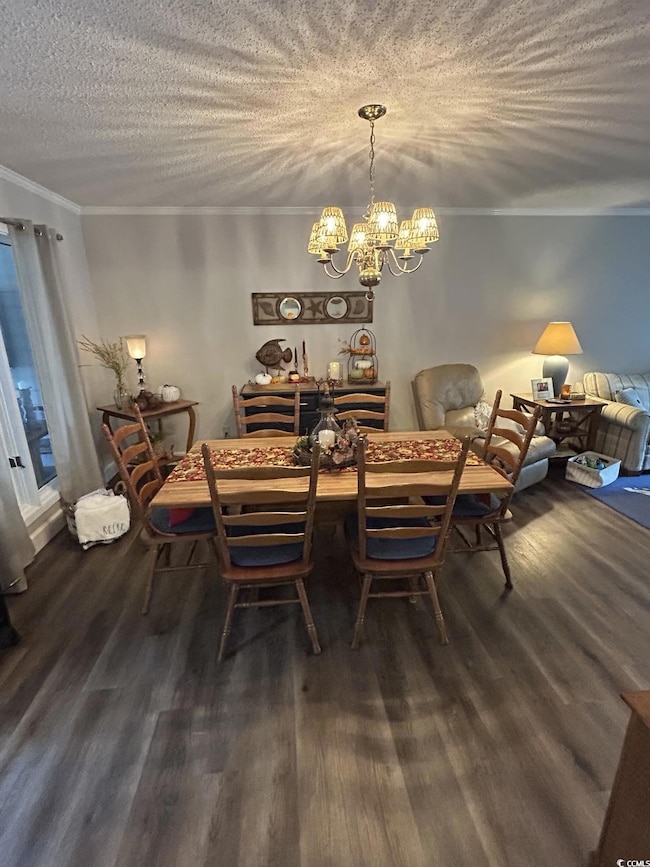 Dining room with crown molding, a chandelier, wood finished floors, and a textured ceiling