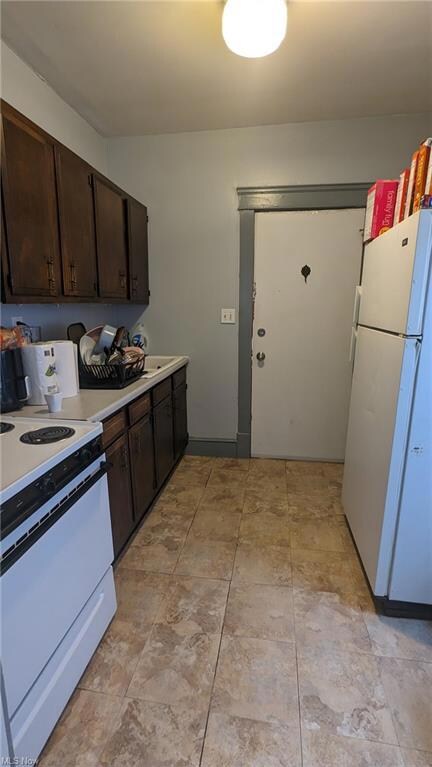 Kitchen featuring white appliances, light tile floors, and dark brown cabinetry