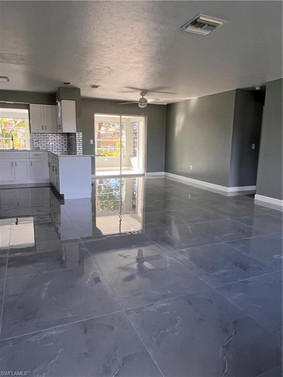 Unfurnished living room featuring ceiling fan, a h