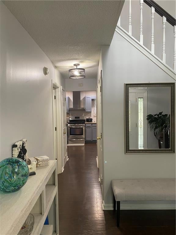 Hall featuring baseboards, a textured ceiling, and