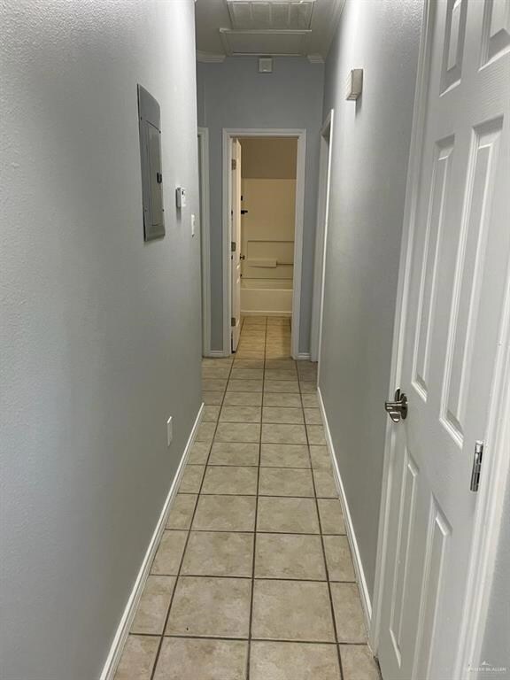Hallway with light tile patterned floors and electric panel