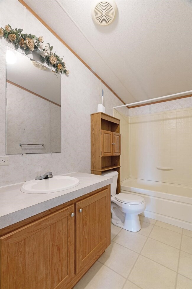 Bathroom with light tile patterned flooring, shower / washtub combination, vanity, lofted ceiling, and ornamental molding