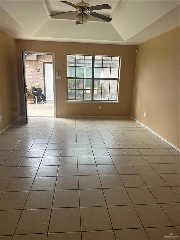 Unfurnished room featuring a raised ceiling, ceiling fan, baseboards, and tile patterned floors