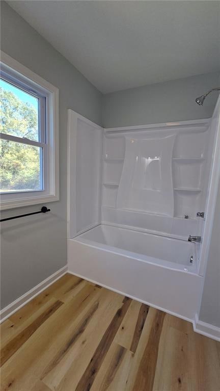 Bathroom with shower / tub combination and light wood-type flooring