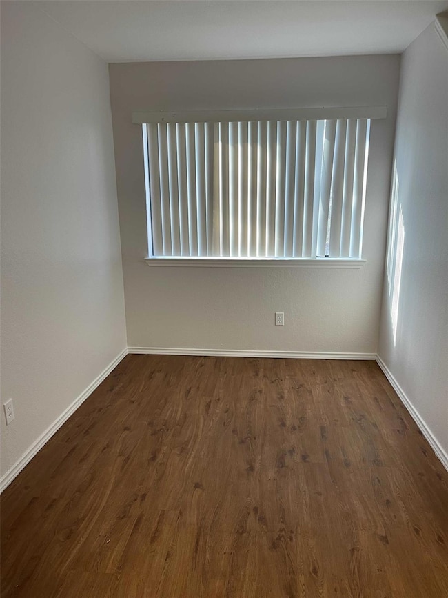 Unfurnished room with dark wood-style floors and b