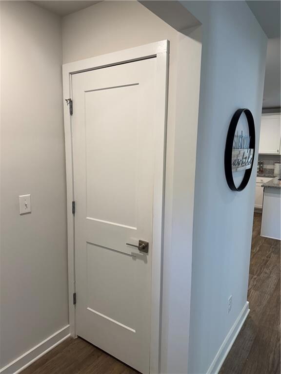 Hallway featuring baseboards and dark wood finishe