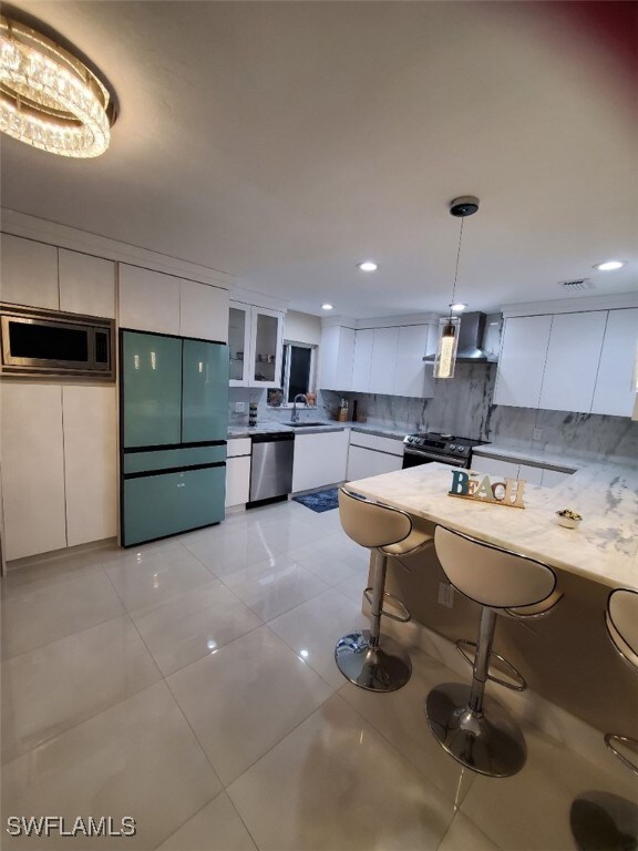 Kitchen with a kitchen bar, sink, white cabinetry,