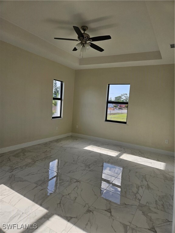 Spare room with a raised ceiling, ceiling fan, bas