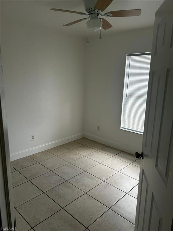 Unfurnished room with light tile patterned flooring, ceiling fan, and baseboards