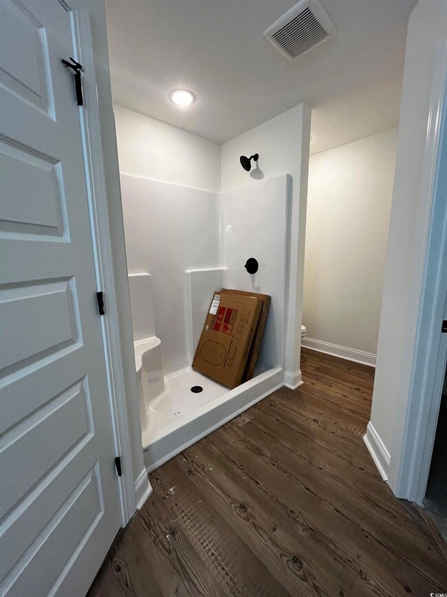Bathroom featuring a shower, hardwood / wood-style