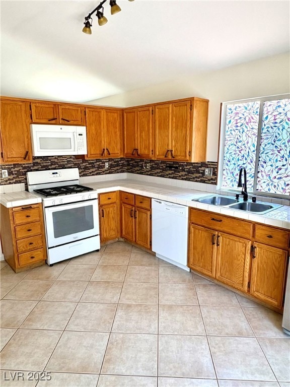 Kitchen featuring white appliances, a sink, backsp