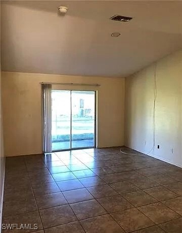 Spare room with vaulted ceiling, visible vents, an
