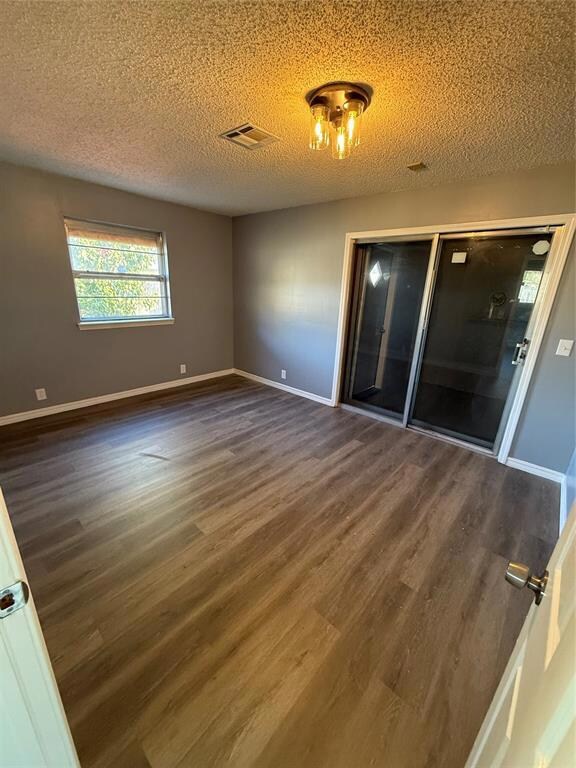 Unfurnished room with dark hardwood / wood-style flooring and a textured ceiling
