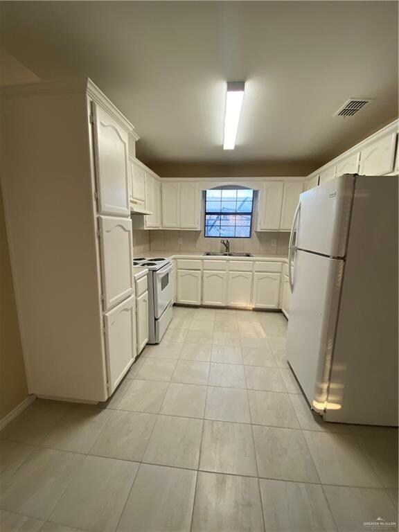 Kitchen with range, visible vents, a sink, exhaust hood, and fridge