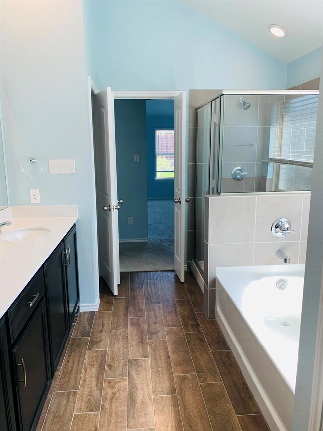 Bathroom with vanity, lofted ceiling, and separate shower and tub
